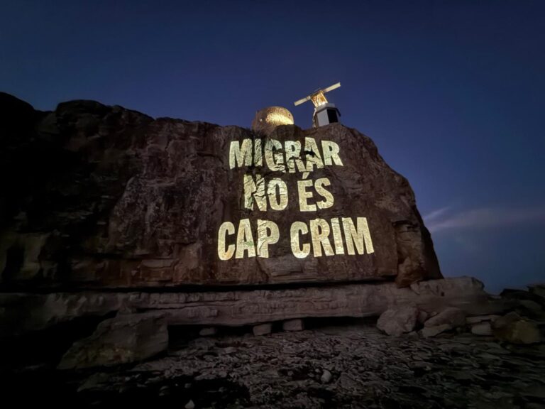 Proyección del Grupo de Acción Antifronteras Laissez Passer, en el marco de una campaña que, en verano de 2025, proyectó en la Torre de en Beu -donde se encuentra el IVE, el radar del sistema de vigilancia de embarcaciones marítimas-, da la bienvenida a las personas migrantes en 22 idiomas. | Fotografía de Laissez Passer